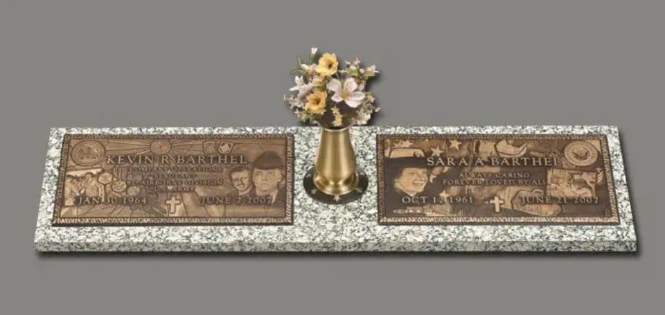 A marble table with two plaques and a vase of flowers.