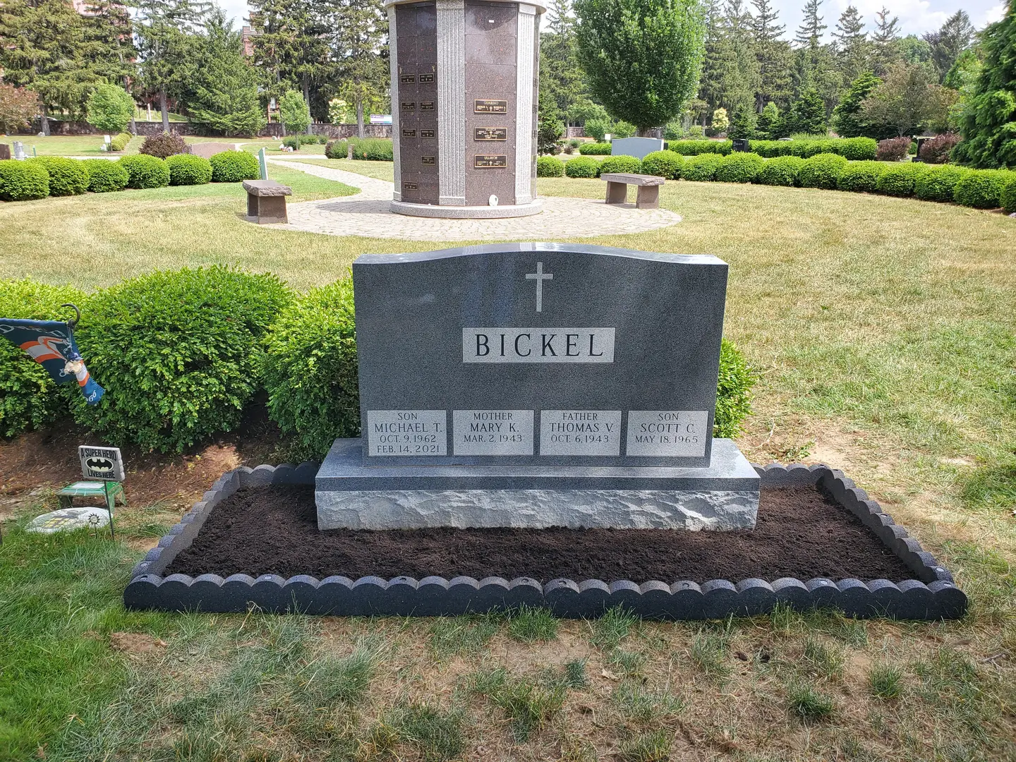 A grave in the middle of a field with bushes around it.