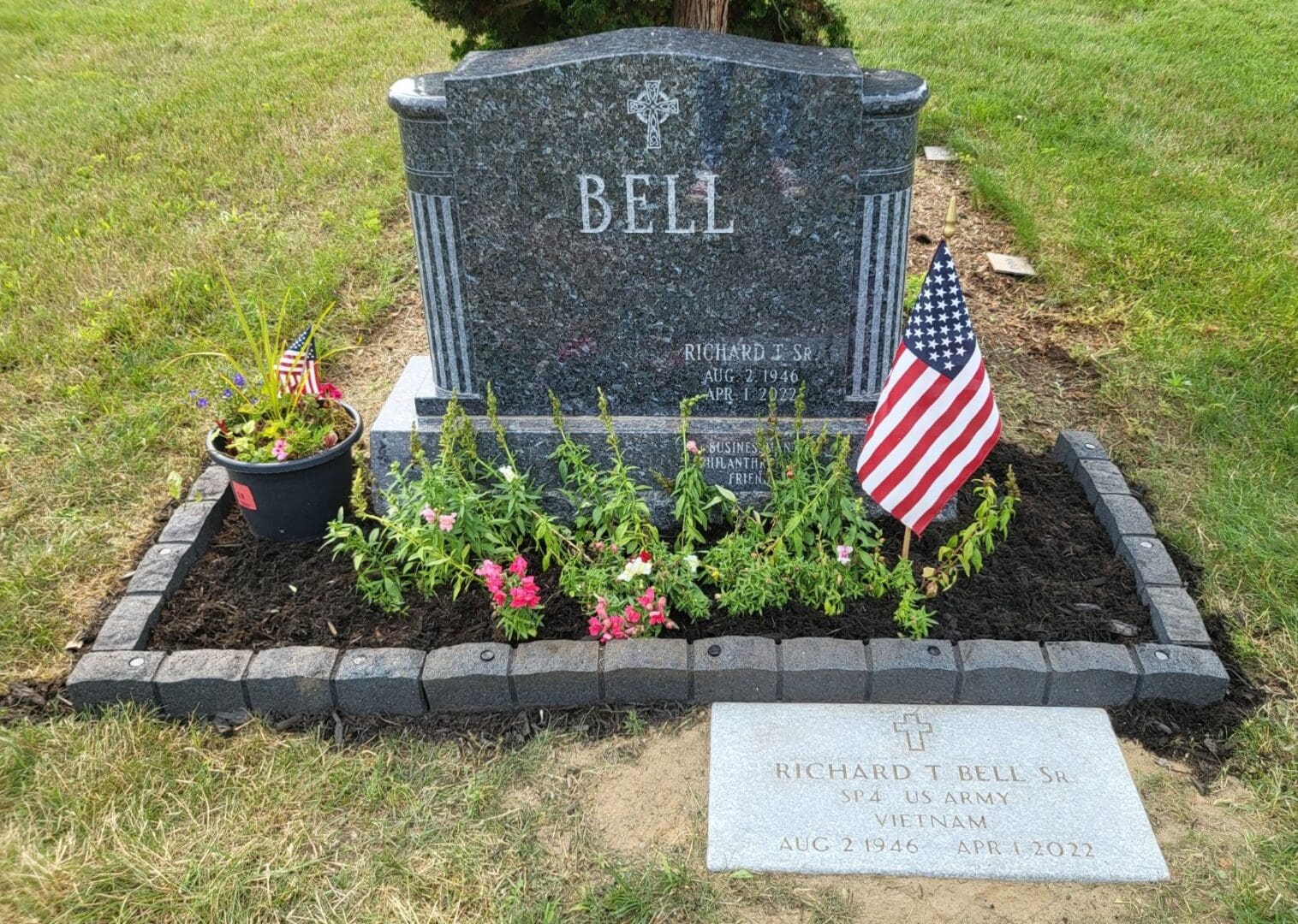 A grave with flowers and a flag in it.