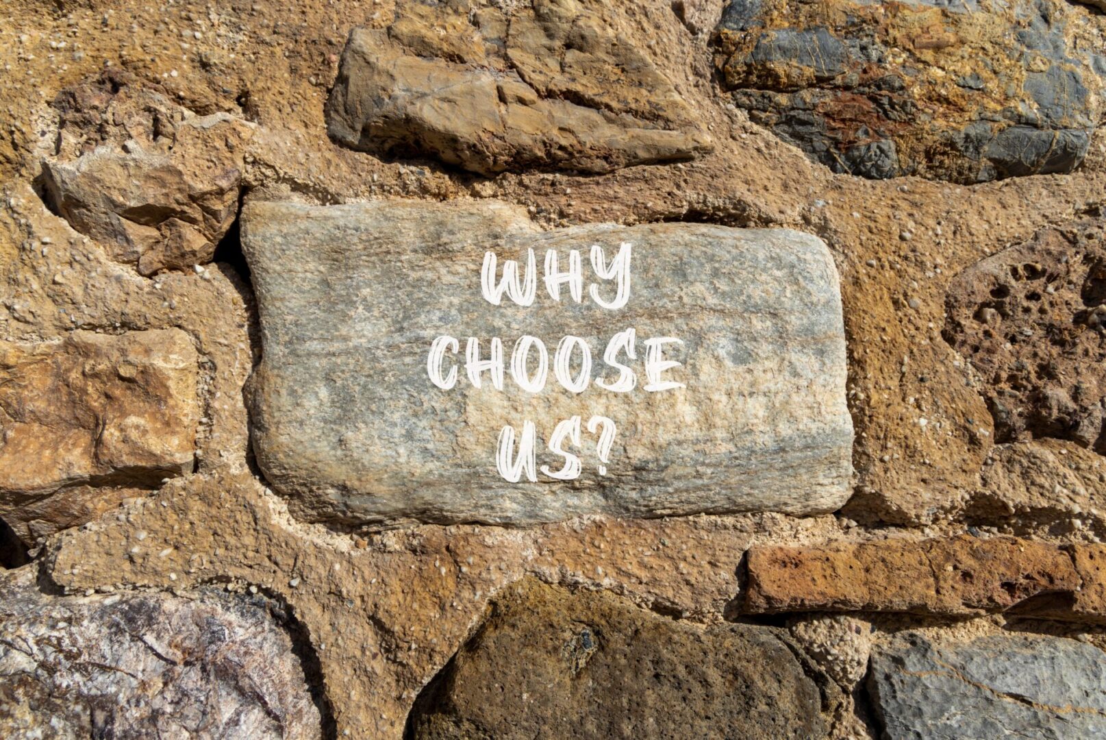 A stone wall with the words " why choose us ?" written on it.